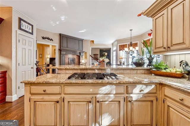 kitchen featuring light stone counters, stainless steel gas cooktop, light brown cabinets, a notable chandelier, and hardwood / wood-style floors