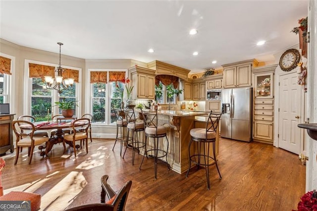 kitchen with light stone countertops, dark hardwood / wood-style flooring, stainless steel appliances, pendant lighting, and a notable chandelier