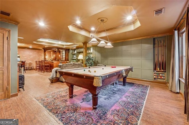 playroom featuring light wood-type flooring, ornamental molding, a raised ceiling, indoor bar, and pool table