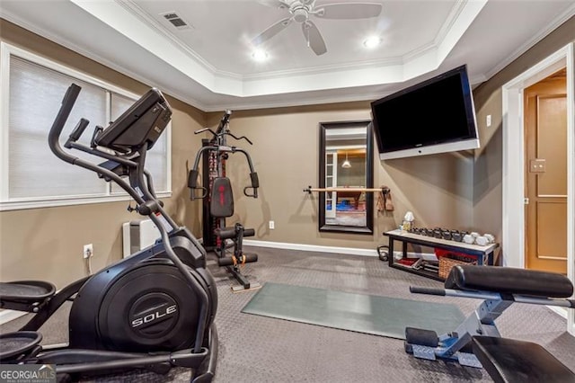 exercise area featuring a tray ceiling, ceiling fan, and crown molding