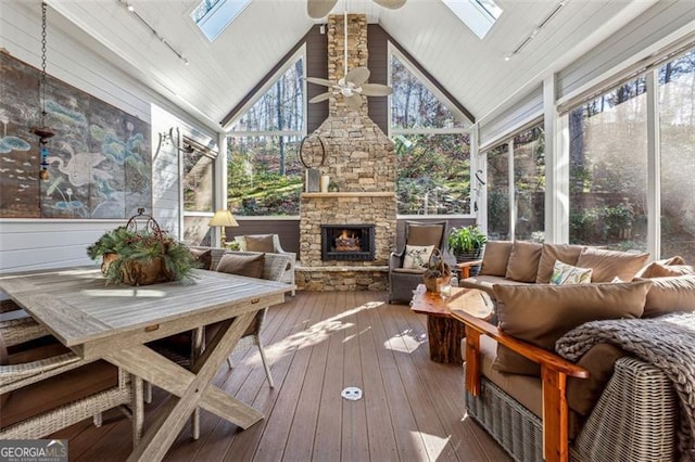 sunroom with a fireplace, ceiling fan, and vaulted ceiling with skylight