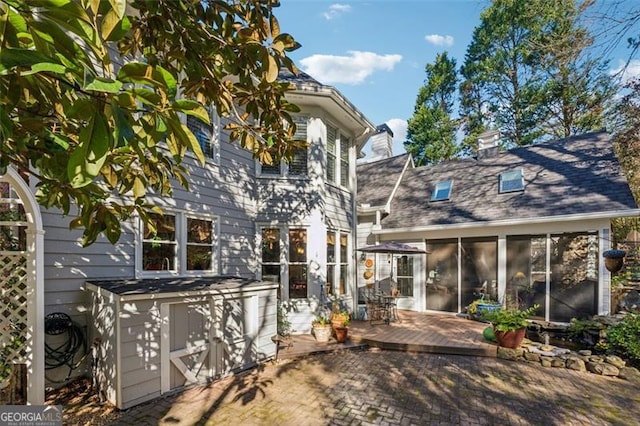 back of property with a sunroom and a patio area