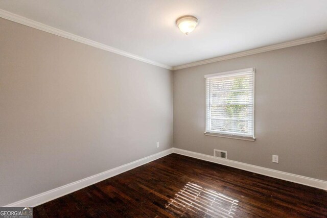 spare room featuring dark wood-type flooring and ornamental molding