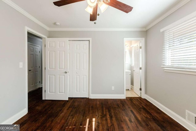 unfurnished bedroom with ensuite bath, ceiling fan, dark hardwood / wood-style flooring, crown molding, and a closet