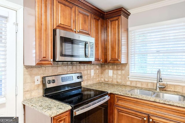 kitchen with decorative backsplash, appliances with stainless steel finishes, light stone countertops, crown molding, and sink