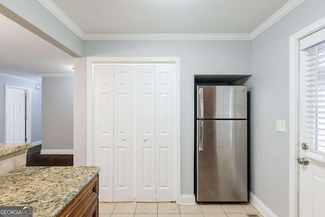 kitchen featuring stainless steel fridge, light tile patterned floors, crown molding, and light stone counters