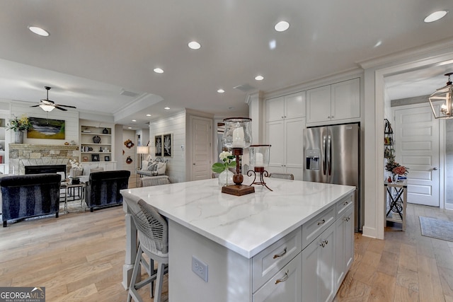 kitchen with white cabinets, a center island, a fireplace, and light stone countertops