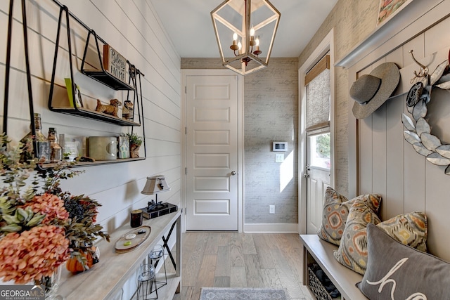 mudroom featuring wooden walls, light hardwood / wood-style flooring, and a chandelier