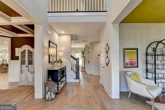 entryway featuring beamed ceiling, light wood-type flooring, ornamental molding, and coffered ceiling