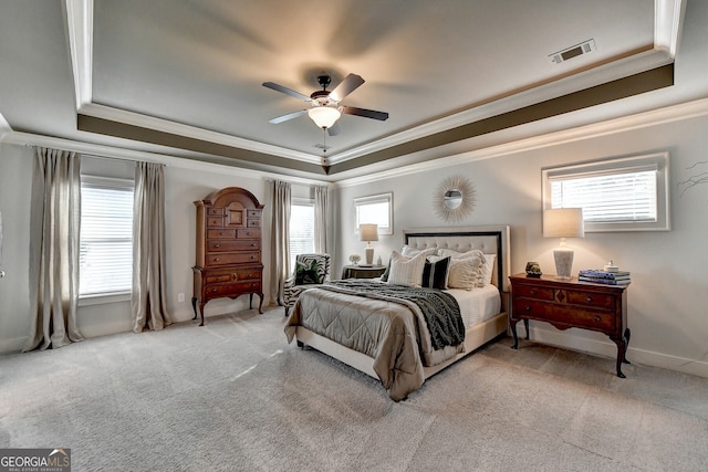 bedroom featuring a tray ceiling, ceiling fan, ornamental molding, and light colored carpet