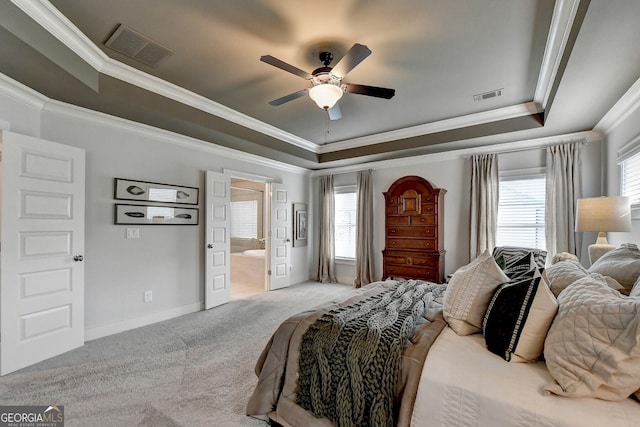 carpeted bedroom featuring ceiling fan, a raised ceiling, ornamental molding, and ensuite bathroom