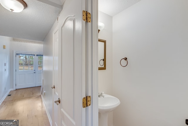 bathroom featuring a textured ceiling and hardwood / wood-style flooring