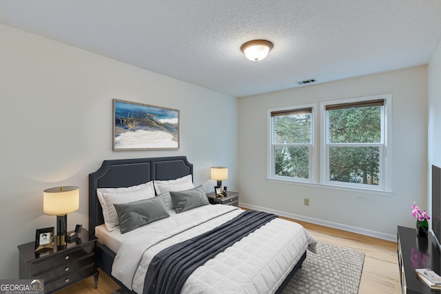 bedroom with a textured ceiling and light hardwood / wood-style flooring