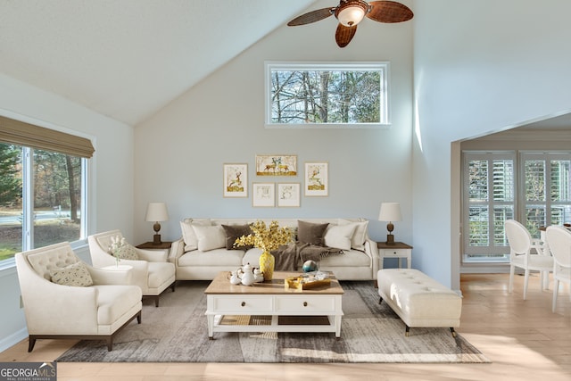 living room featuring ceiling fan, light hardwood / wood-style flooring, and a towering ceiling