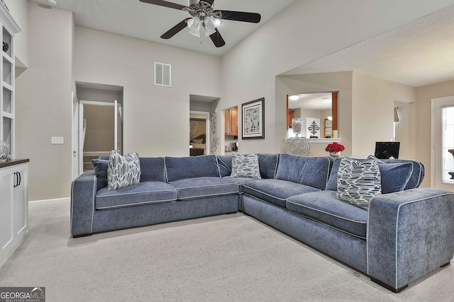 living room with a textured ceiling, light colored carpet, vaulted ceiling, and ceiling fan