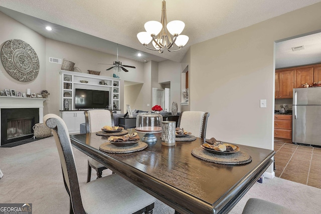 tiled dining area with a textured ceiling and ceiling fan with notable chandelier