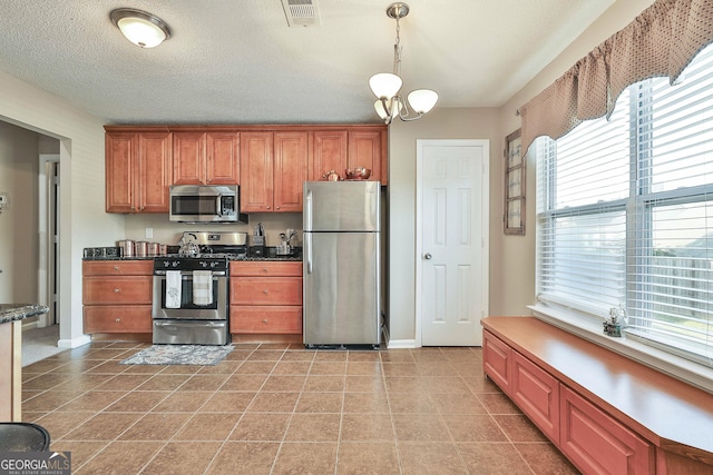 kitchen featuring a chandelier, a textured ceiling, decorative light fixtures, light tile patterned floors, and appliances with stainless steel finishes