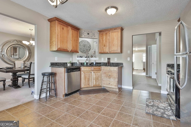 kitchen featuring sink, stainless steel appliances, an inviting chandelier, a textured ceiling, and carpet