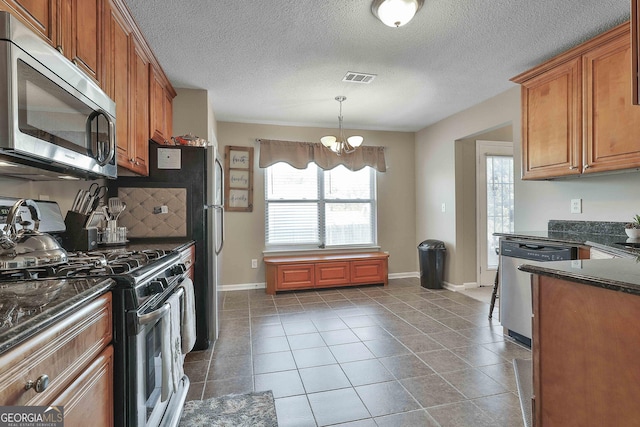 kitchen featuring plenty of natural light, stainless steel appliances, hanging light fixtures, and a chandelier