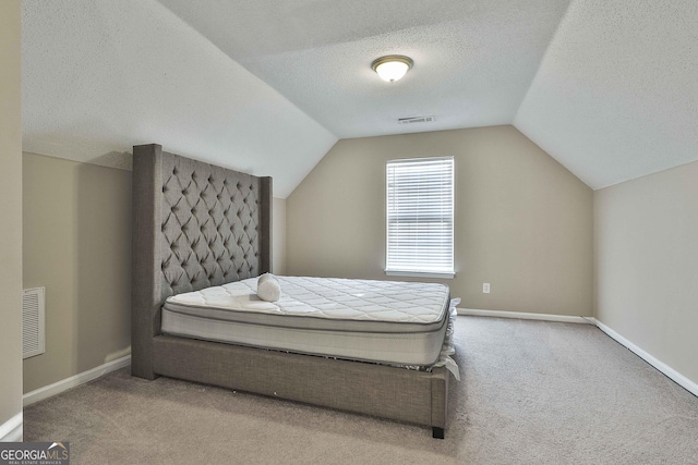 bedroom featuring lofted ceiling, light colored carpet, and a textured ceiling