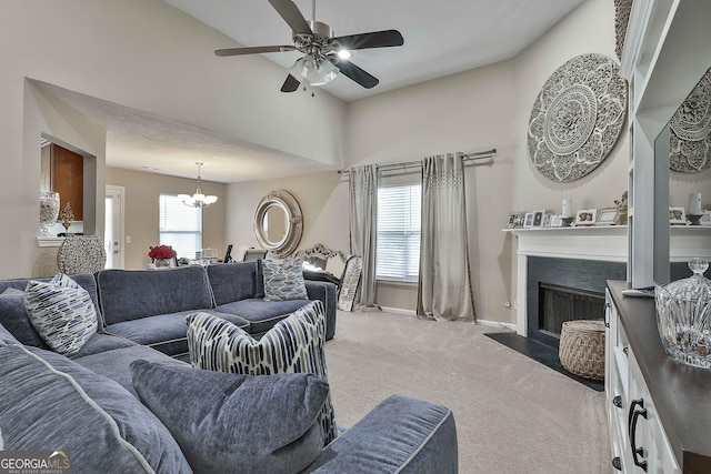 carpeted living room with ceiling fan with notable chandelier