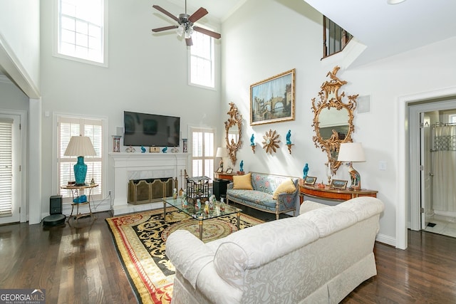 living room featuring a towering ceiling, dark hardwood / wood-style floors, ceiling fan, and ornamental molding