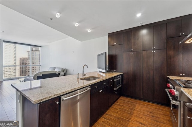 kitchen with sink, light stone countertops, appliances with stainless steel finishes, dark hardwood / wood-style flooring, and dark brown cabinetry