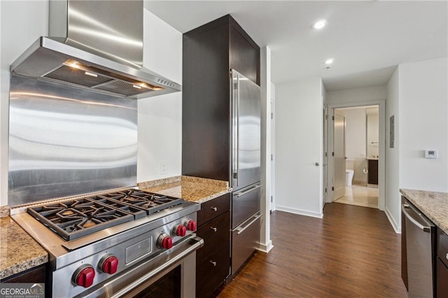 kitchen with dark hardwood / wood-style flooring, light stone counters, wall chimney exhaust hood, dark brown cabinetry, and high end appliances