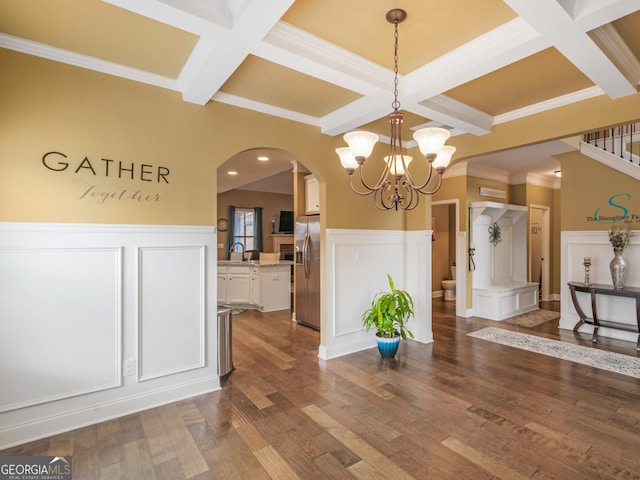 unfurnished dining area with a chandelier, dark hardwood / wood-style flooring, crown molding, and coffered ceiling