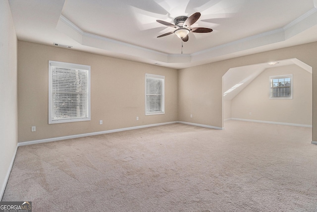 carpeted empty room with a raised ceiling, ceiling fan, and crown molding