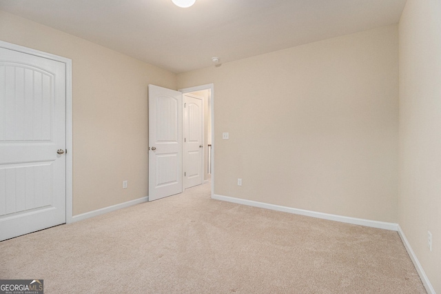 unfurnished bedroom with light carpet and a closet