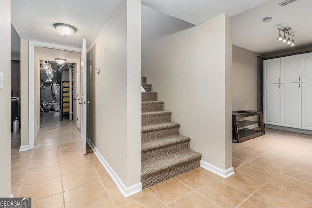 stairs featuring tile patterned flooring and track lighting