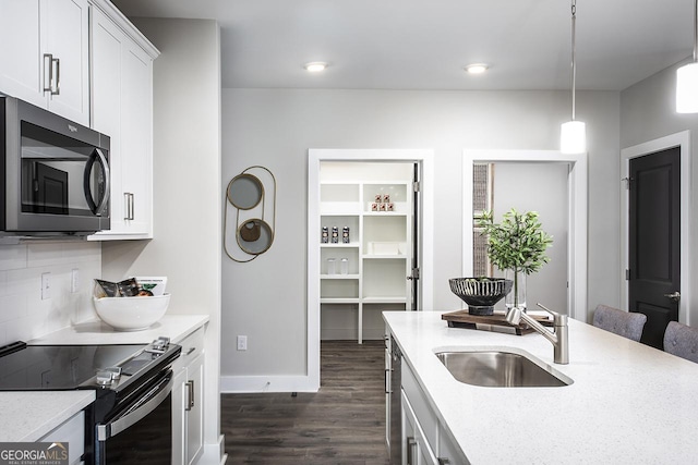 kitchen with stainless steel appliances, sink, white cabinetry, backsplash, and pendant lighting