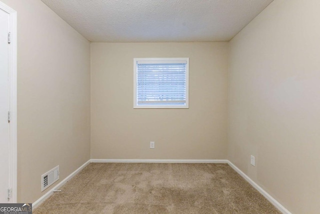 spare room featuring light carpet and a textured ceiling