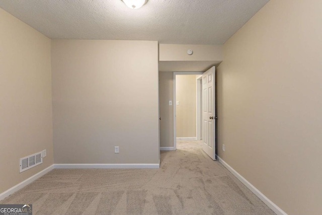 empty room with a textured ceiling and light colored carpet