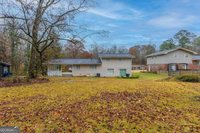 rear view of property featuring a lawn and central air condition unit