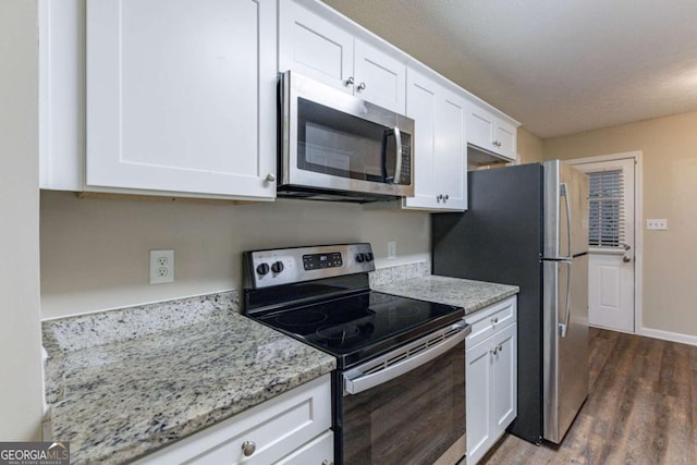 kitchen with light stone countertops, white cabinetry, dark wood-type flooring, and appliances with stainless steel finishes