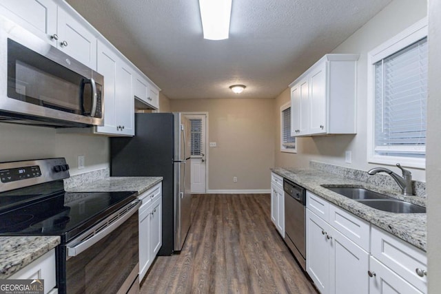 kitchen featuring white cabinets, sink, light stone countertops, dark hardwood / wood-style flooring, and stainless steel appliances