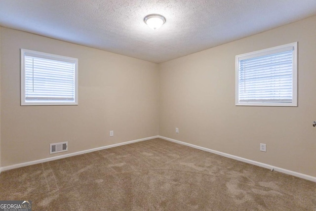 empty room with light carpet and a textured ceiling