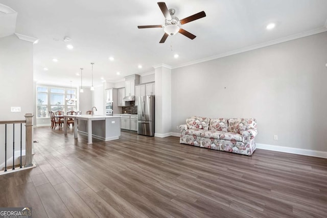 unfurnished living room featuring ceiling fan, crown molding, dark hardwood / wood-style floors, and sink