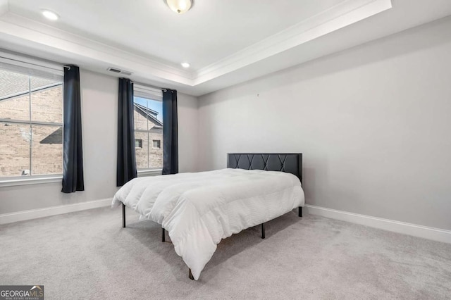 bedroom with light colored carpet, crown molding, and a tray ceiling