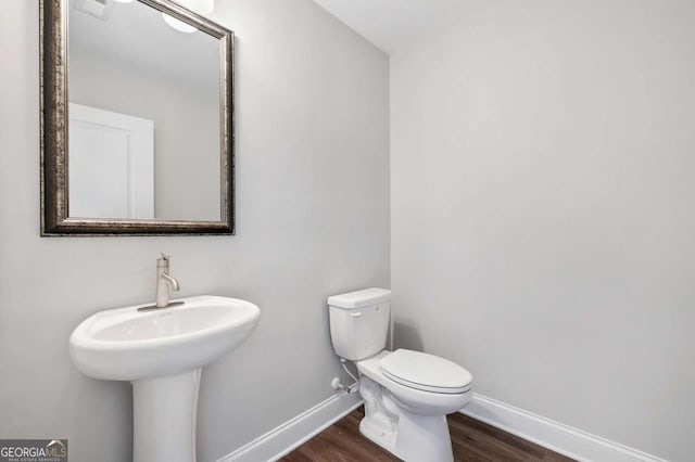 bathroom with toilet, wood-type flooring, and sink