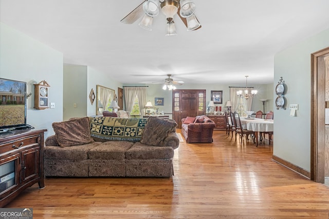 living room featuring ceiling fan with notable chandelier and light wood-type flooring