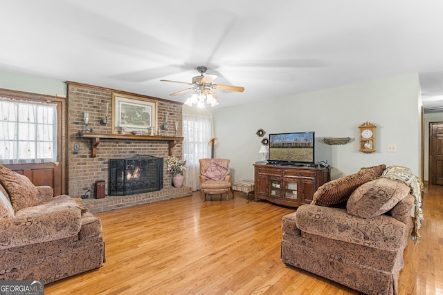 living room featuring ceiling fan, light hardwood / wood-style floors, and a fireplace