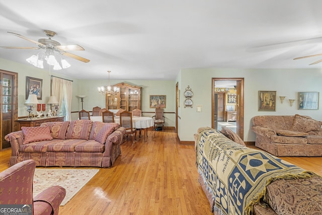 living room featuring ceiling fan with notable chandelier and light wood-type flooring