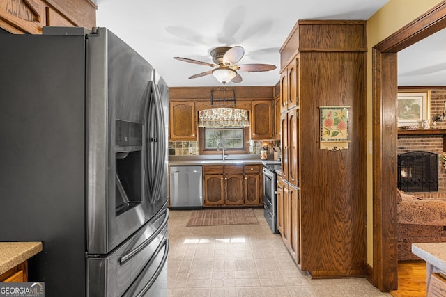 kitchen featuring ceiling fan, sink, a fireplace, and appliances with stainless steel finishes