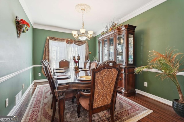 dining area with dark hardwood / wood-style floors, an inviting chandelier, and crown molding