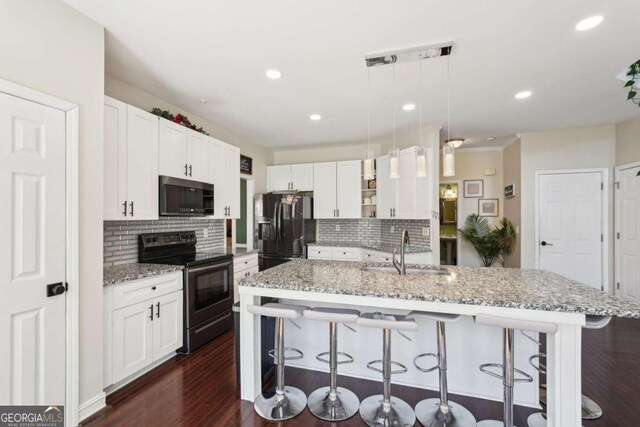 kitchen featuring a kitchen breakfast bar, backsplash, stainless steel appliances, pendant lighting, and a center island with sink