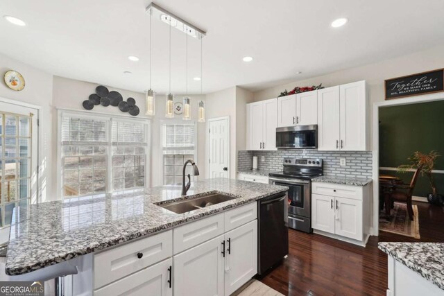 kitchen featuring white cabinets, hanging light fixtures, sink, and appliances with stainless steel finishes