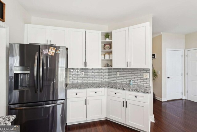 kitchen with white cabinetry, light stone countertops, stainless steel fridge with ice dispenser, and backsplash